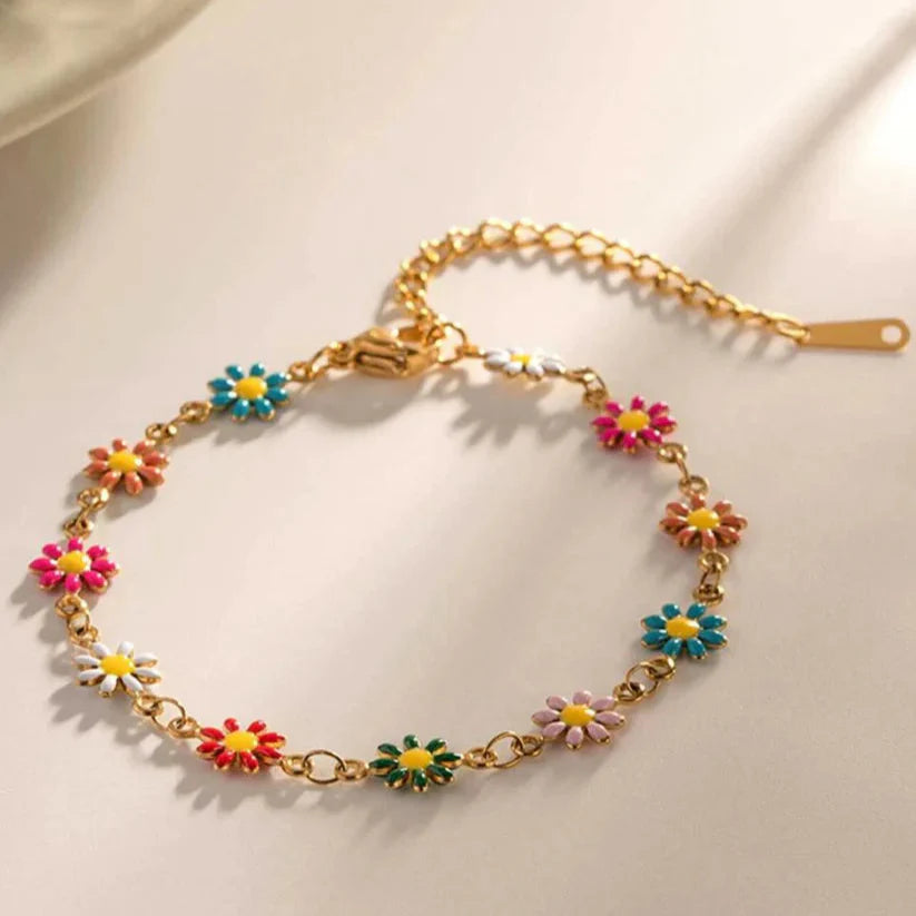Gold bracelet with colorful flower charms on a light background