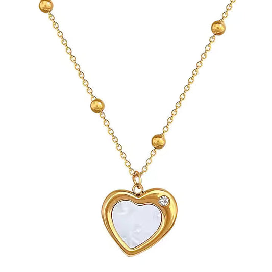Gold necklace with a heart-shaped pendant on a white background